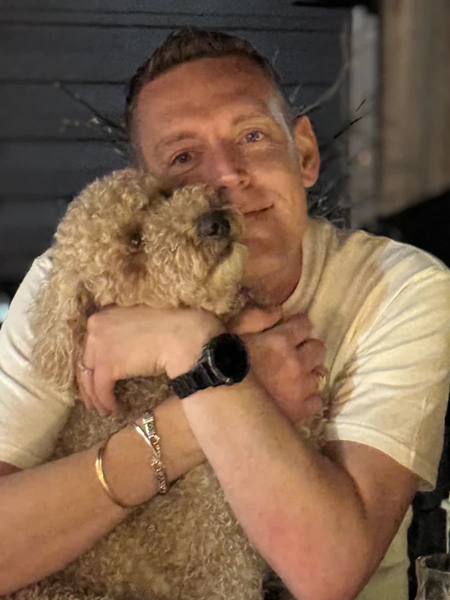 Dave holding Rubble, his small curly-haired dog