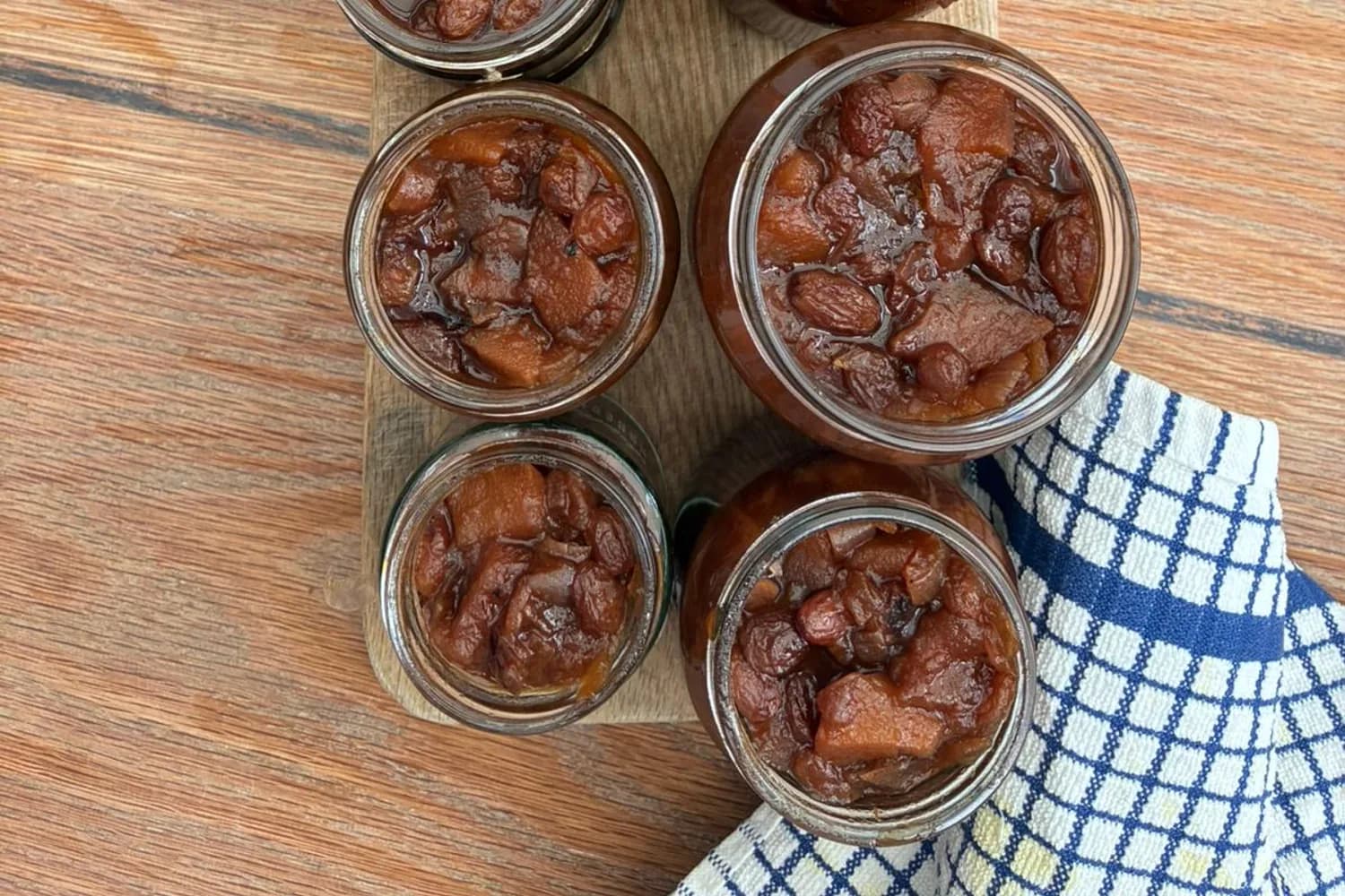 A finished batch of apple and pear chutney cooling in seven glass jars