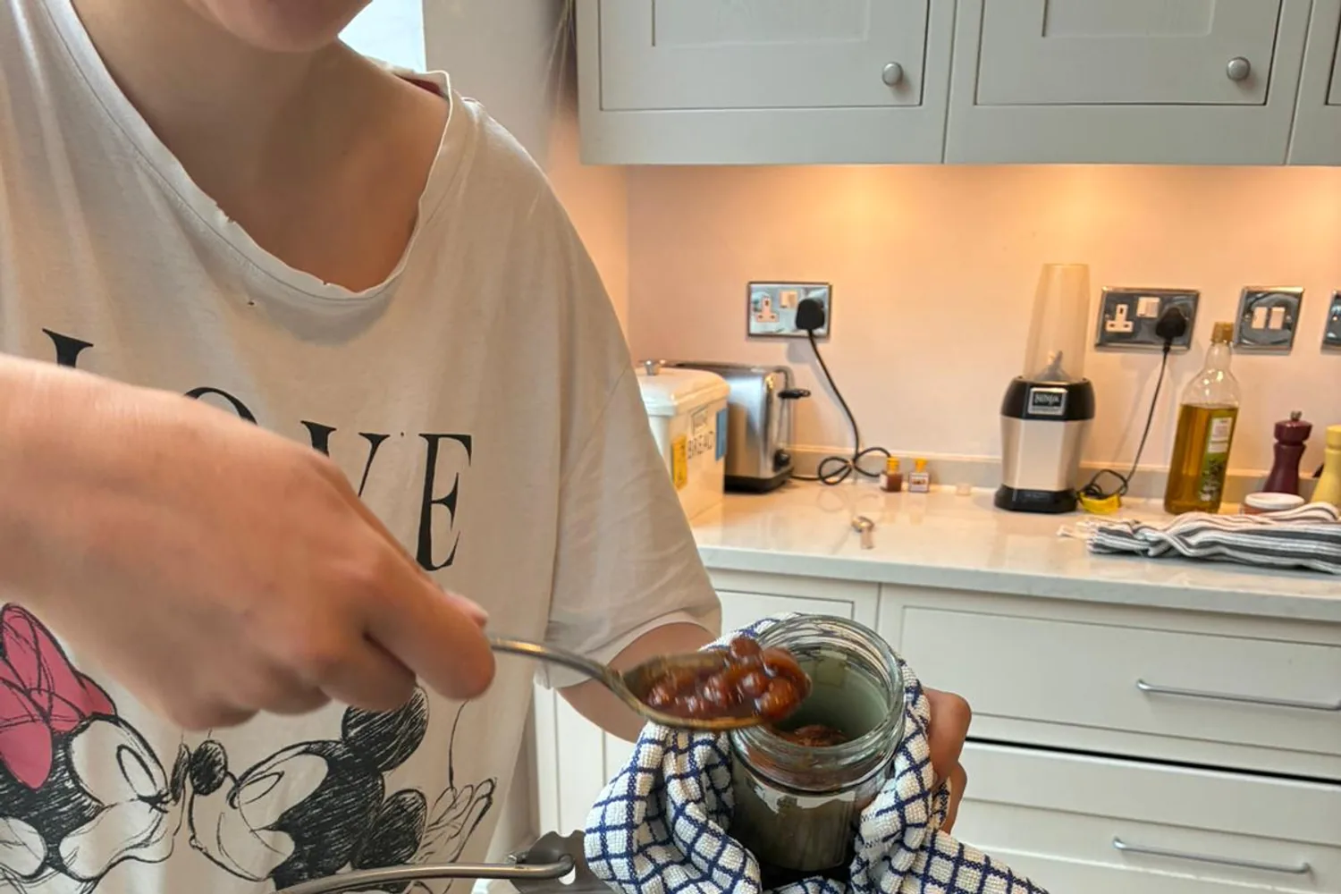 Hot apple and pear chutney being spooned carefully into a prepared glass jar