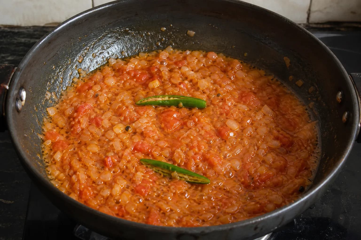 Soft pale onions and broken-down tomatoes bubbling with two slit green chillies