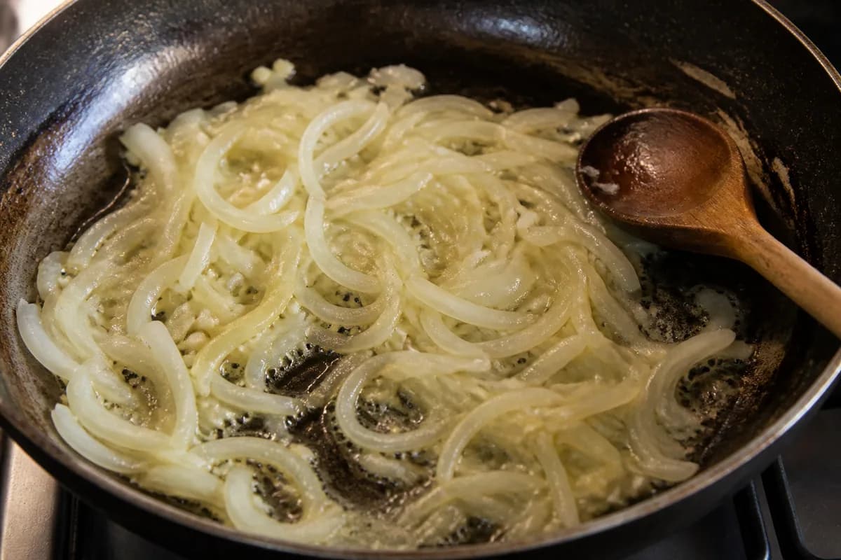Sliced onions and garlic softening in butter in a frying pan
