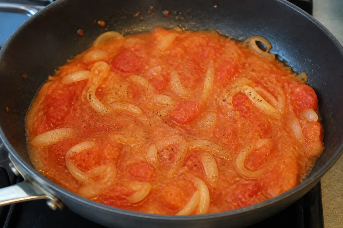 A chunky tomato and onion sauce simmering in a pan